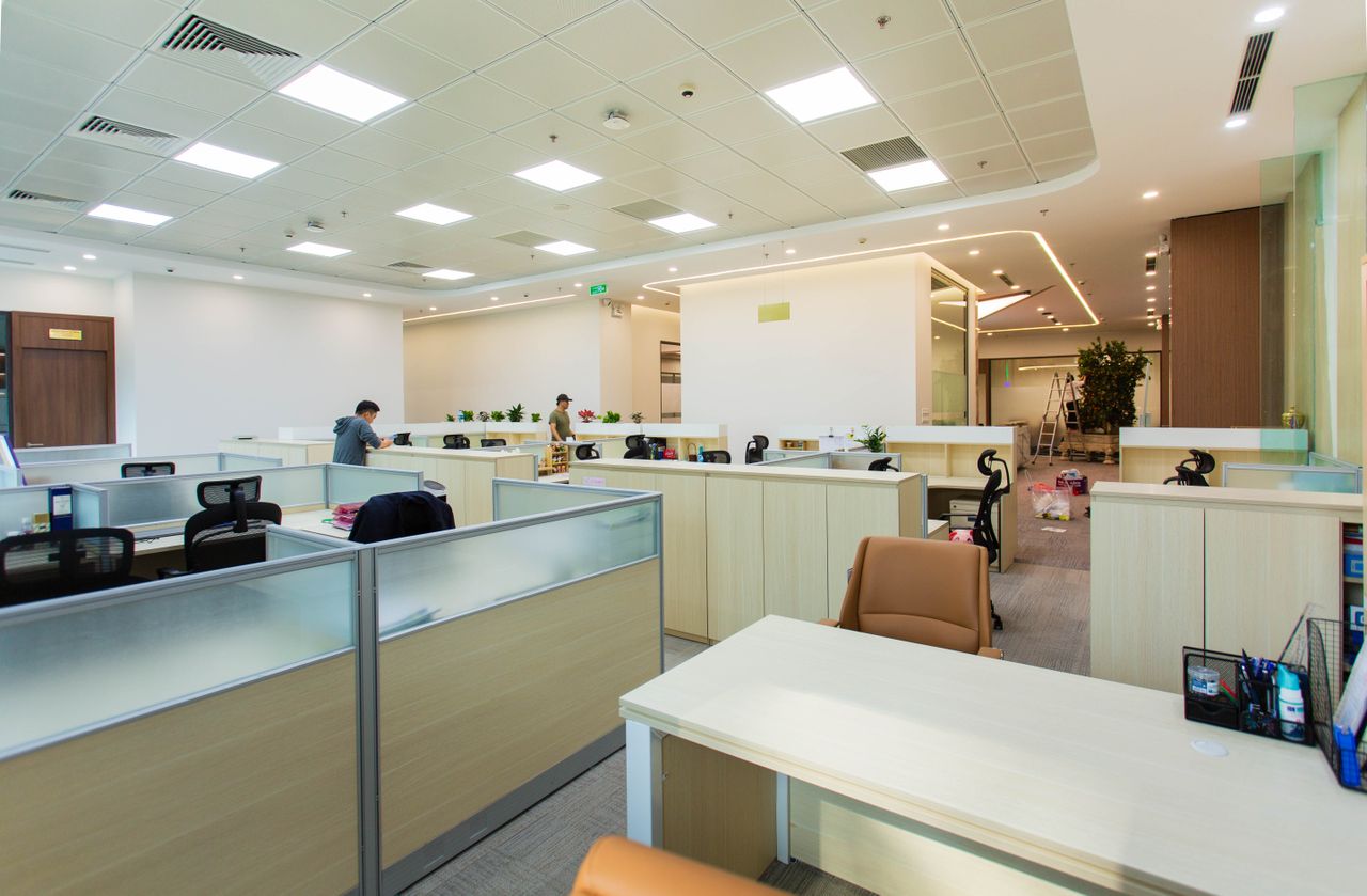 services-01 Bright and spacious office interior featuring open-plan cubicles, modern furniture, and ceiling lights.